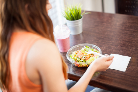 Point of view of a young woman eating a salad and drinking a smoothie at a restaurantの写真素材