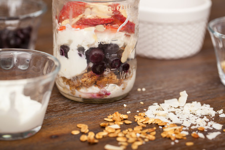 Closeup of some yogurt served in a jar with granola, strawberries, blueberries, nuts and cocount, shown in layersの写真素材