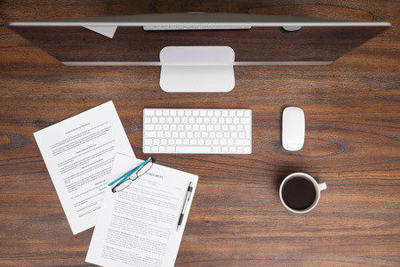 Flat lay of a computer, coffee and some legal documents on a wooden desk in a lawyer's officeの写真素材