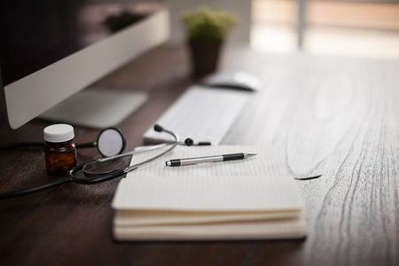 Closeup of the workplace of a doctor with a stethoscope and a notepad with shallow depth of field