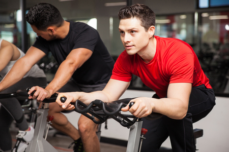 Portrait of an attractive young man doing some cardio on a bicycle and looking focused on his workoutの写真素材
