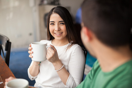 Young man enjoying the company of a beautiful girl in a date at a coffee shopの写真素材