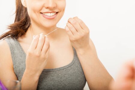 Beautiful woman in the bathroom using dental floss on her teeth, seen up close