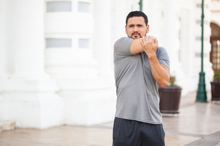 Attractive young man doing some stretching exercises and warming up before going for a run outdoorsの写真素材