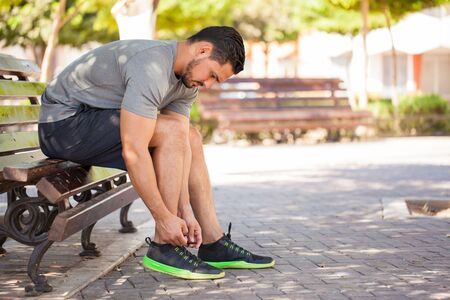 Profile view of an attractive young man tying his shoes and getting ready to go for a run outdoorsの写真素材