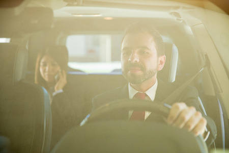 Attractive young male driver taking an important client to her destination. Seen through the windshieldの写真素材
