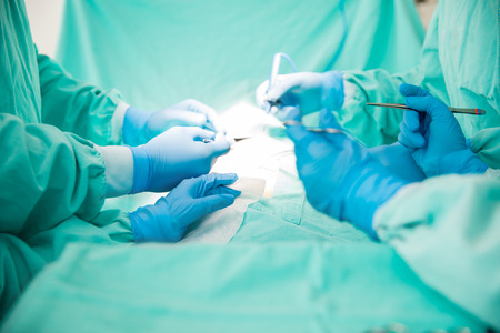 Closeup of four sets of hands of surgeons working on a patient with several instrumentsの写真素材