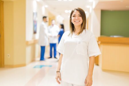 Portrait of a beautiful young nurse walking down a hospital hallway and smilingの写真素材
