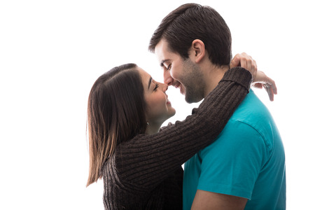 Backlit view of a young couple in love getting close to each other before a kiss against a white backgroundの写真素材