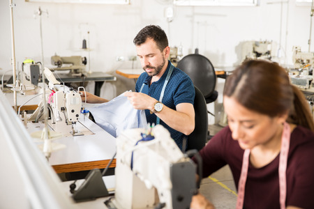 Couple of workers sewing some clothing in a production line in a textile factoryの写真素材