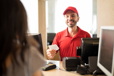 Portrait of a handsome Hispanic worker selling tickets to a customer at the movie theater