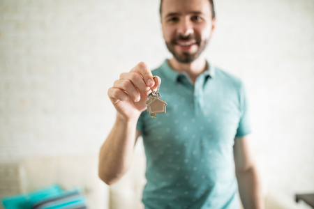 Close up shot of a good looking Hispanic man showing the keys of his new apartment