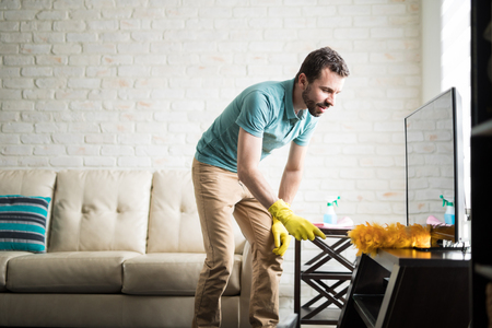 Attractive Latin man in his 30s doing house chores to maintain his apartment cleanの写真素材