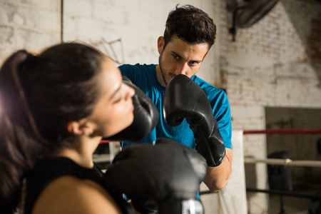Hispanic male boxer punching a woman during a box fight in a boxing ringの写真素材