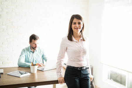 Portrait of a cute young female office assistant helping her boss and smilingの写真素材