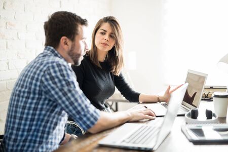 Man explaining his ideas to his female colleague about a new project at the officeの写真素材