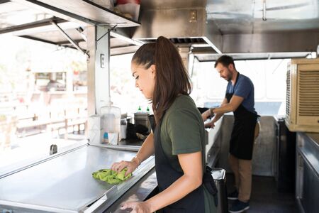 Pretty brunette cleaning her food truck and getting ready to cook some food for her customers
