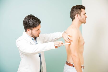 Profile view of a shirtless young man getting an evaluation at a nutritionist's officeの写真素材