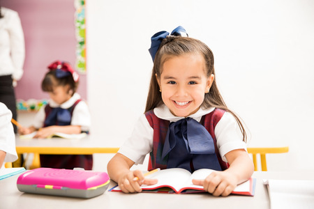 Portrait of a pretty Hispanic preschool girl in uniform loves to learn  and enjoys her day at schoolの写真素材