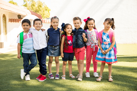 Full length view of a group of kids standing outside of preschool on a sunny day and smilingの写真素材