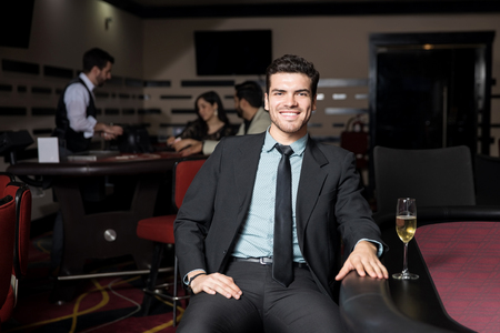 Good looking young man wearing a suit and having some fun in a casino playing pokerの写真素材