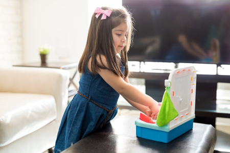Sweet little hispanic girl washing her hands in toy hand wash sink in living room at homeの写真素材