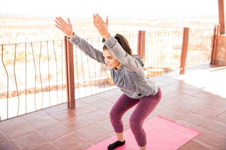 Beautiful young hispanic woman doing chair pose yoga workout at healthy center