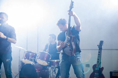 Man playing electric guitar in live concert with bright light and smokeの写真素材