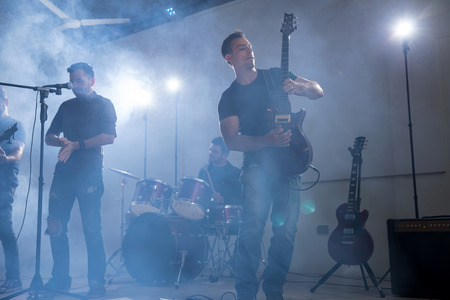 Guitarist playing guitar with his band on rock concert stage