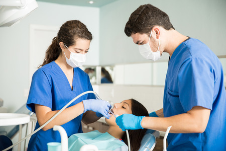 Medical coworkers treating teenage patient with dental equipment at clinicの写真素材