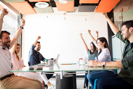Ambitious workers keeping hands up to show their positive mood in break time in meeting roomの写真素材