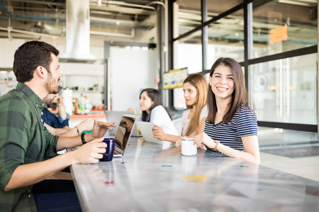 Beautiful young hispanic woman sitting at cafeteria with coworkers having coffee