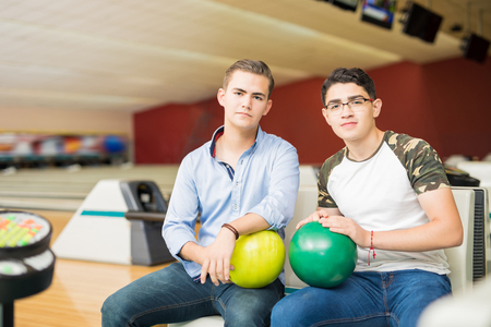 Confident teenage friends hanging out in a bowling alley and getting ready to competeの写真素材