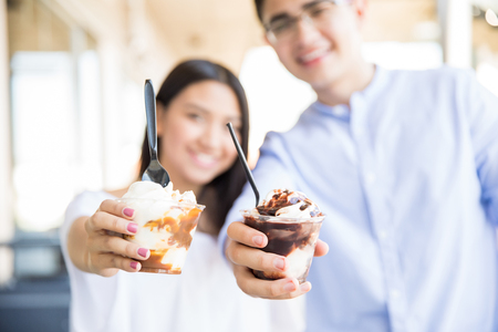 Defocused teenage couple showing icecream cups in mallの写真素材