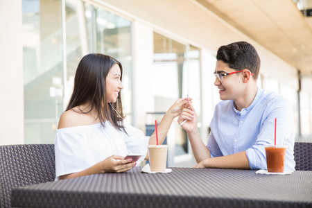 Teenage couple listening to music on earphones while having drinks at cafe in shopping mallの写真素材