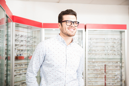 Handsome young man choosing eyeglasses frame in optical storeの写真素材