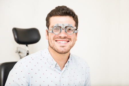 Portrait of handsome smiling man with trial lens at optician center while looking at cameraの写真素材