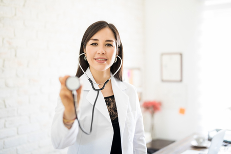 Portrait of attractive latin female physician holding her stethoscope in frontの写真素材