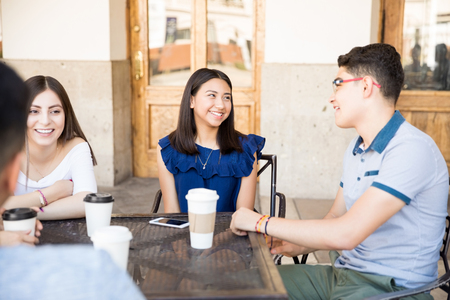 Group of teenage people enjoying some coffee together in a restaurant and talkingの写真素材