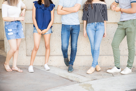 Low section shot of teenage boys and girls standing by a wall togetherの写真素材