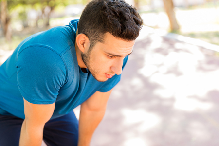 Exhausted young man taking rest after long run in parkの写真素材