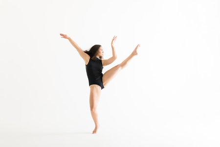 Full length of female performer in black leotard practicing ballet moves over white backgroundの写真素材