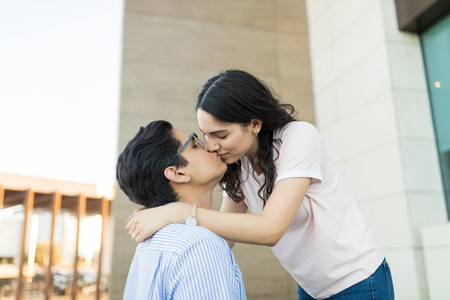 Romantic girlfriend and boyfriend kissing on lips outside shopping mallの写真素材