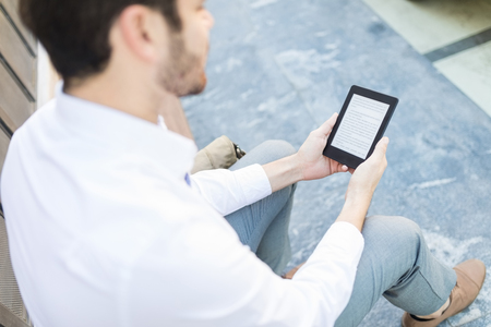 High angle view of businessman using an e-book on footpathの写真素材