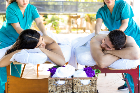People in love getting back massage from massagers at wellness resort during honeymoon vacationの写真素材