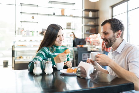 Loving couple having coffee and chouxs while enjoying date in bakery