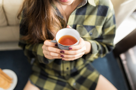 Midsection of young woman holding warm beverageの写真素材