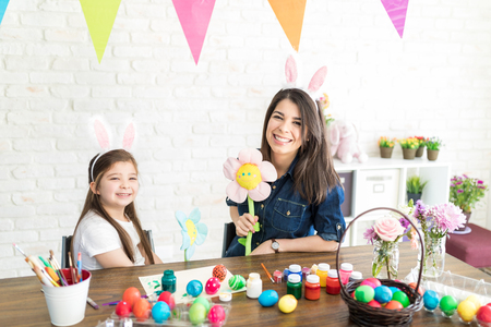 Creative mother and daughter with toy flowers preparing for Easter celebrationの写真素材