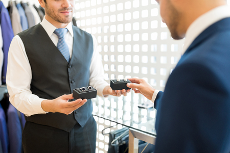 Midsection of salesman advising to buy right pair of cufflinks to customerの写真素材