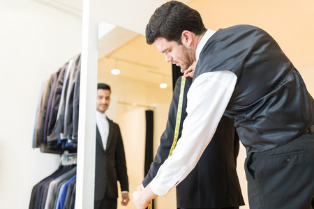 Seamster taking measurement of suit to alter it as per client's requirementの写真素材